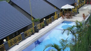 En swimmingpool med ett kaklat poolområde, omgiven av gula räcken och palmer.