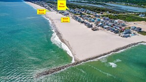 An aerial view of a coastal residential area with beach access, a row of houses, and a river in the background. - GREAT OCEAN VIEWS -- 5 Bedroom, 5.5 Bath, 2 Living Rooms (Ocean Isle Beach)