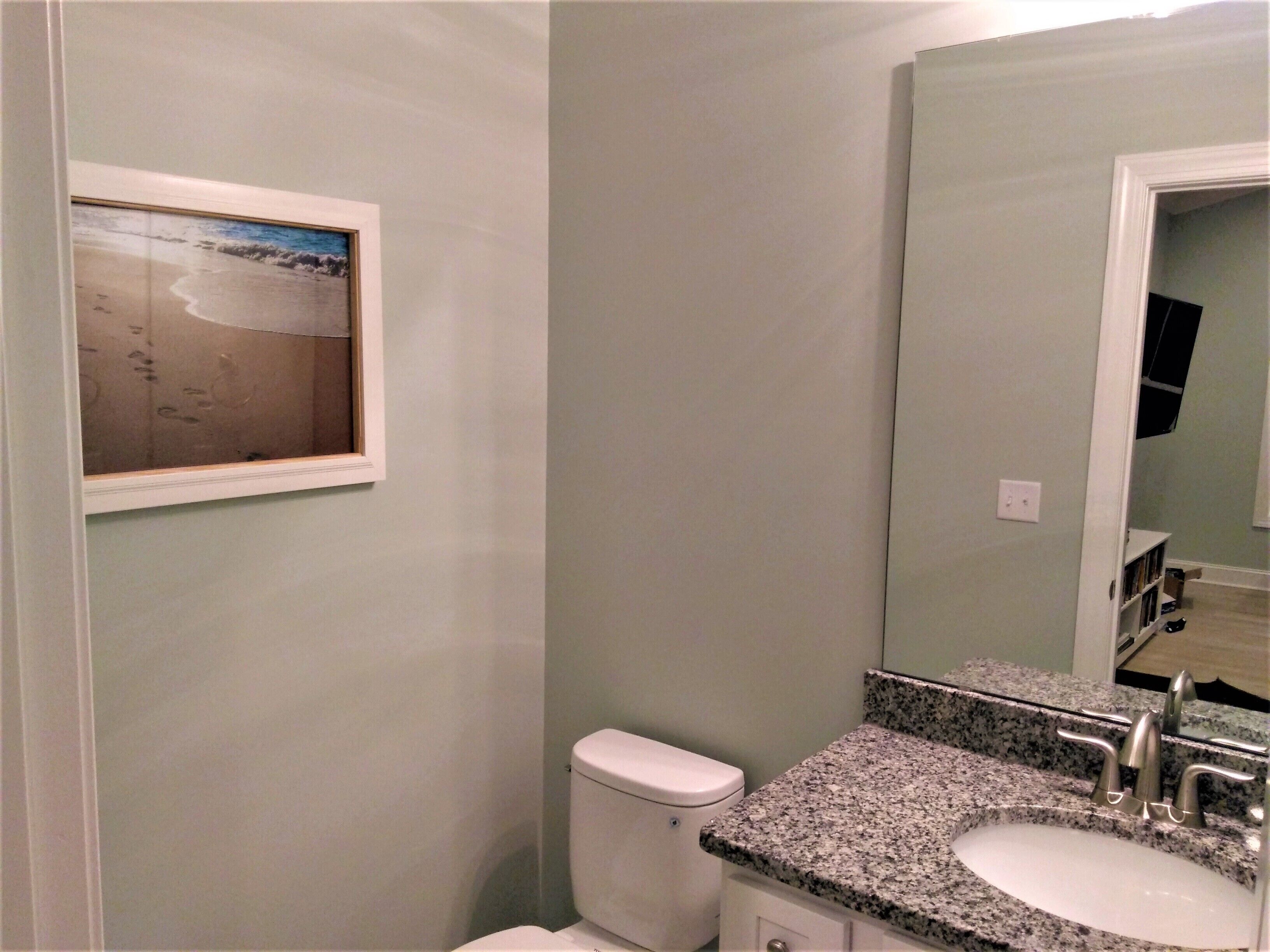 A bathroom with a toilet, sink, and a framed picture on the wall.