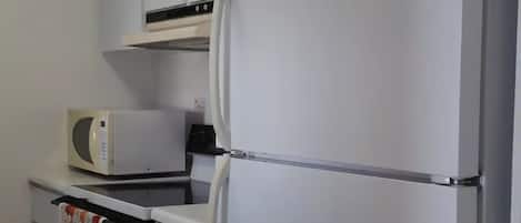 Una cocina con armarios blancos, microondas y refrigerador.