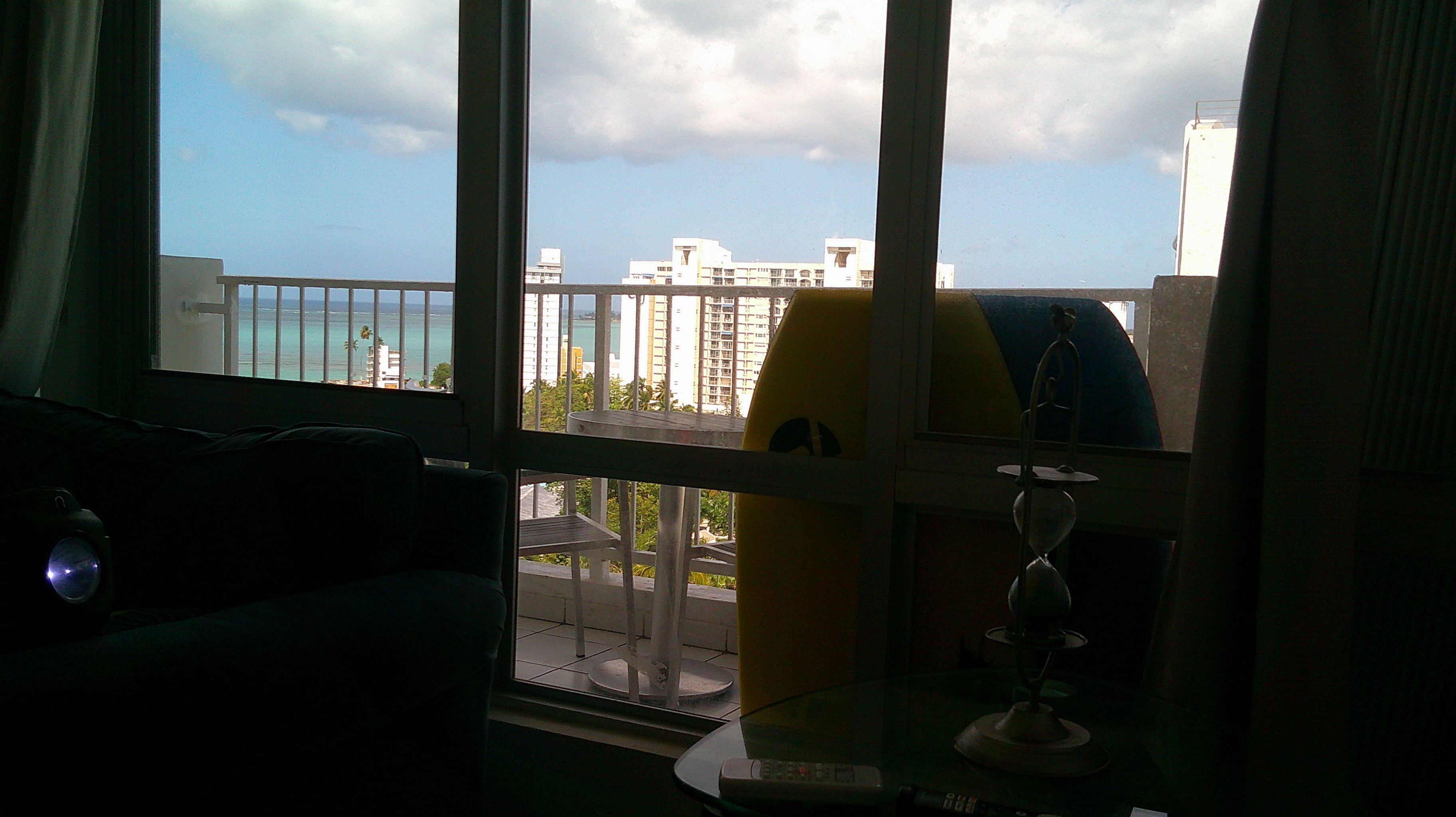 Una habitación con vista a un balcón, una tabla de surf y un telescopio.