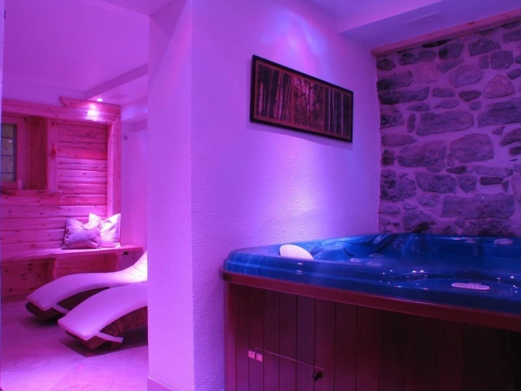 Une salle de spa équipée d’un bain à remous, de bancs en bois et d’un mur en pierre.