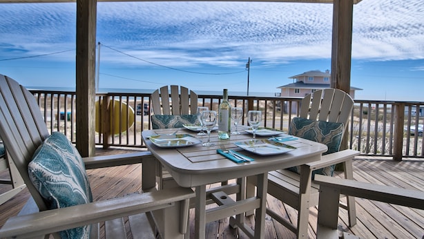 A wooden deck with a table set for two, overlooking a beach. - Blue Wave 🌊 Beach Front View  🌞 Private Pool 🌴 Most Reviews on SGI (Apalachicola)