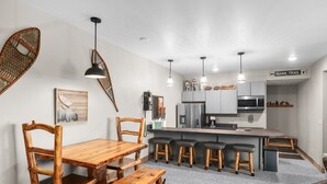 Una cocina moderna con una isla central, taburetes de bar y una mesa de comedor con sillas.