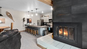 Una cocina moderna con una isla central, taburetes de bar y una chimenea.