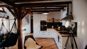 Een moderne keuken met witte kasten, een houten aanrecht en een hangende lamp.