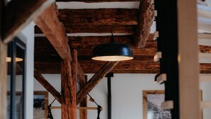 Een rustiek interieur met zichtbare houten balken en hanglampen.
