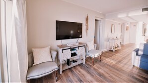 A living room with a television, a sofa, a chair, and a small table.