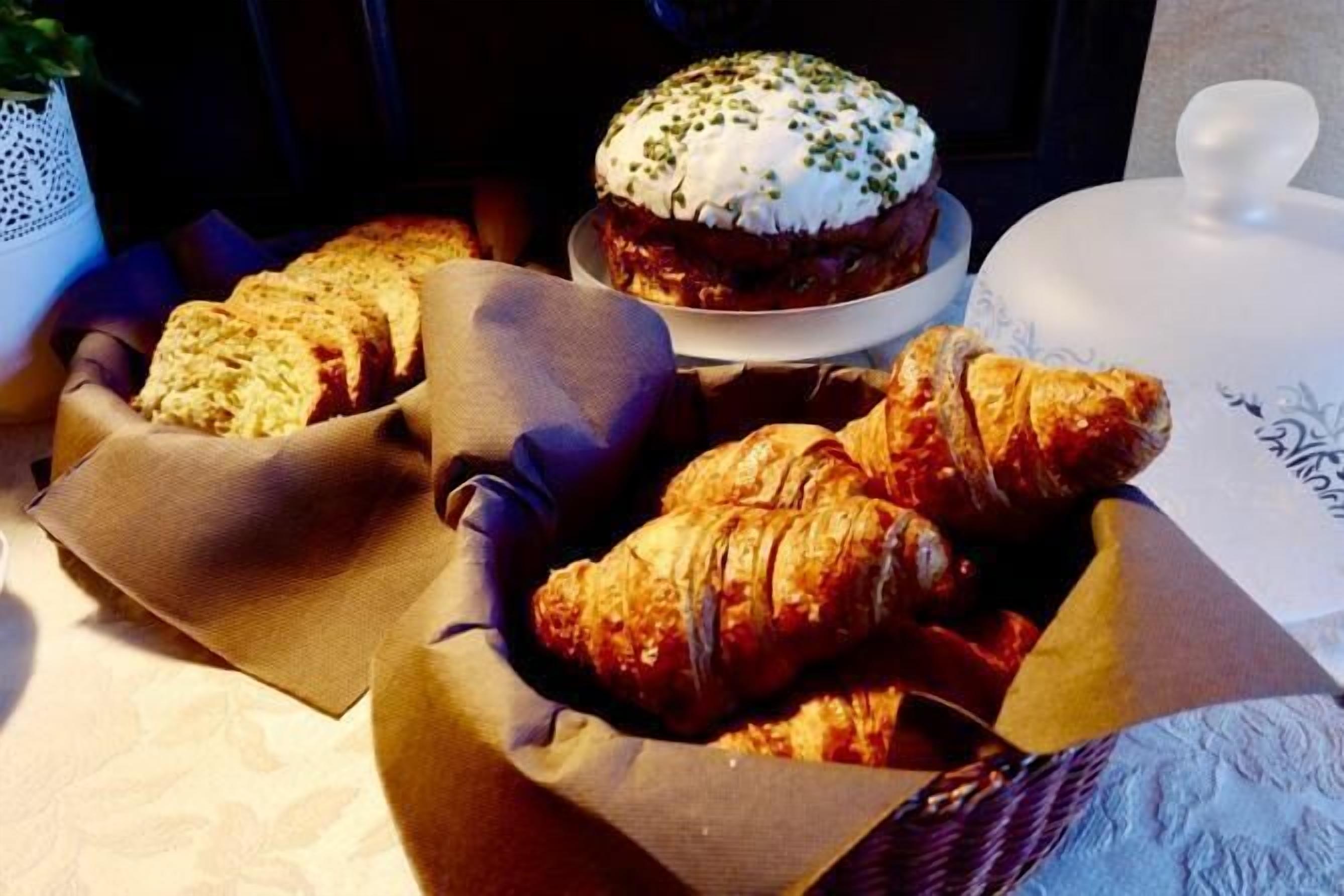 Een tafel met brood en gebak, waaronder croissants en een belegd broodje.