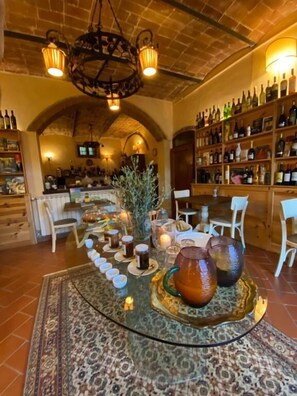 A bar area with a variety of bottles, a round table with glasses, and a patterned rug. - Barco Mediceo (Carmignano)