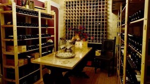 A wine cellar with wooden racks and a table with a wine glass. - Barco Mediceo (Carmignano)