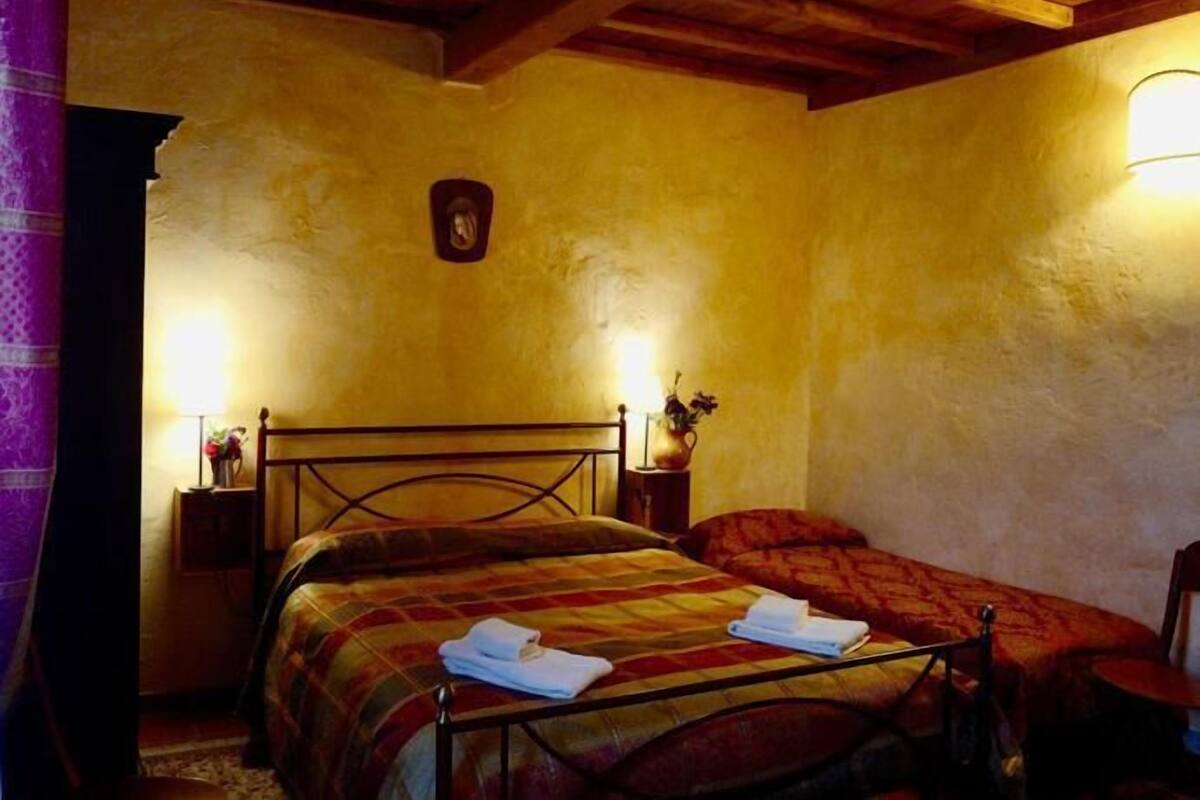 A bedroom with a wooden bed frame, a nightstand with a lamp, and a wall-mounted light fixture.