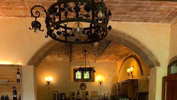 A breakfast buffet setup in a rustic dining area with a brick archway, wooden furniture, and a chandelier. - Barco Mediceo (Carmignano)