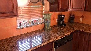 A kitchen with wooden cabinets, a granite countertop, a coffee maker, and various kitchen utensils.