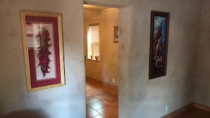A hallway with tiled flooring and two framed artworks on the walls.