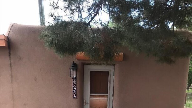 A rustic building with a door, a lantern, and a large pot outside.