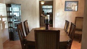 A dining area with a wooden table and chairs, a ceiling fan, and a cabinet with glass doors.