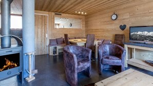 Ein Holzblockhaus-Interieur mit Kamin, Sitzecke und Fernseher.