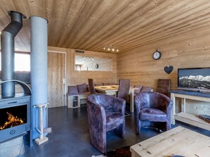 Interior de una cabaña de troncos con chimenea, zona de estar y televisor.