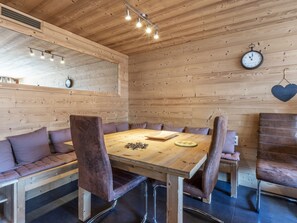 A wooden-paneled room with a round table, leather chairs, a clock, and a heart-shaped decoration.