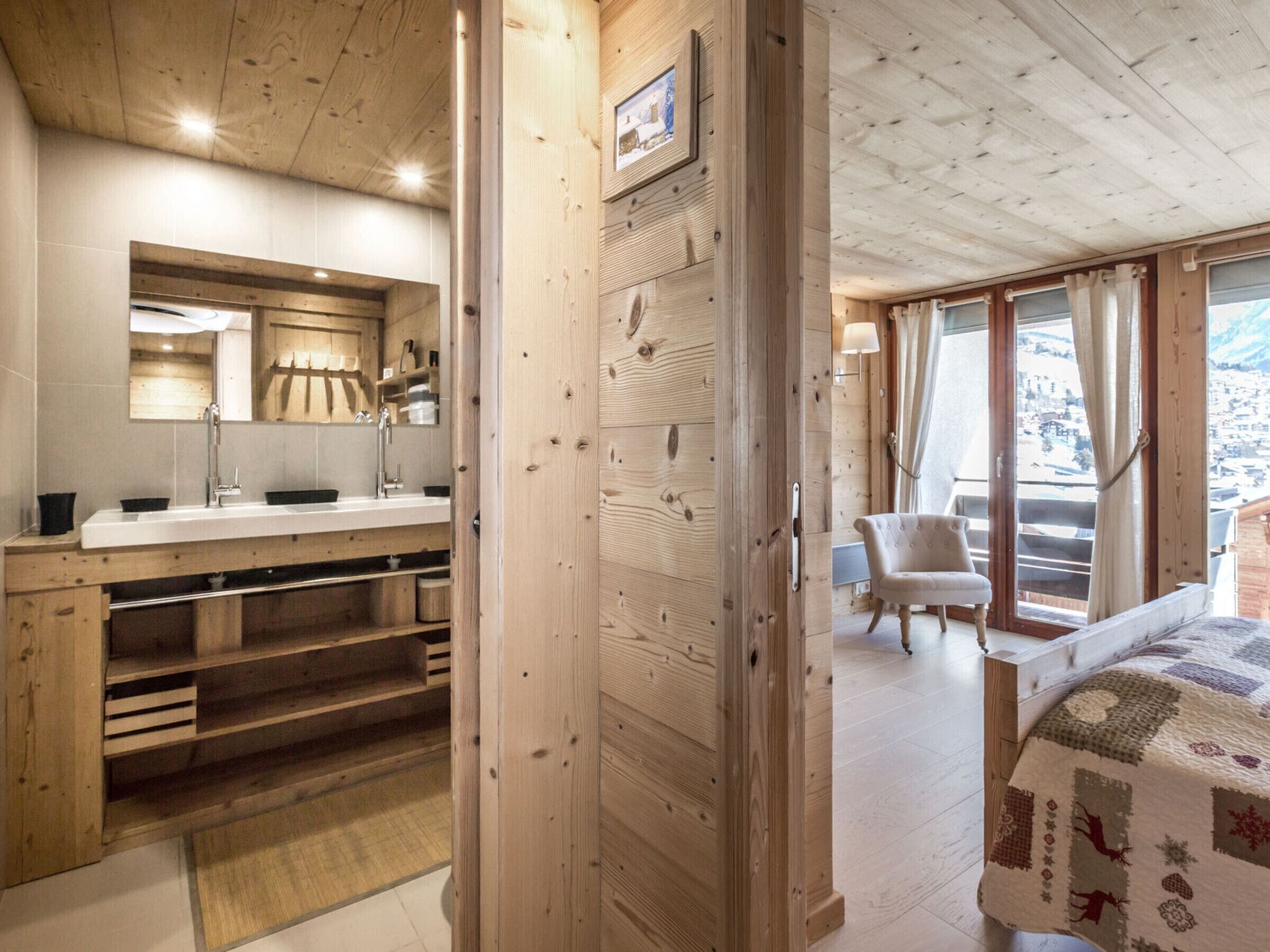 Een houten interieur met een badkamer, een bed en uitzicht op buiten.