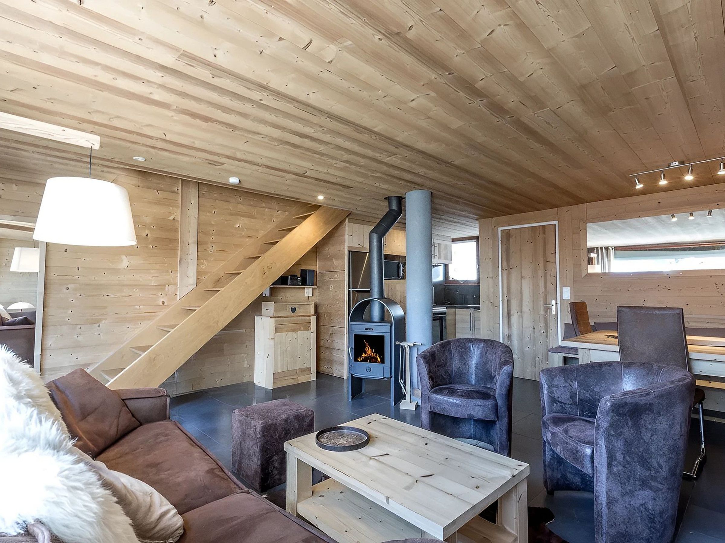 Ein modernes Interieur mit Holzboden, Kamin, Sofa und zwei Sesseln.