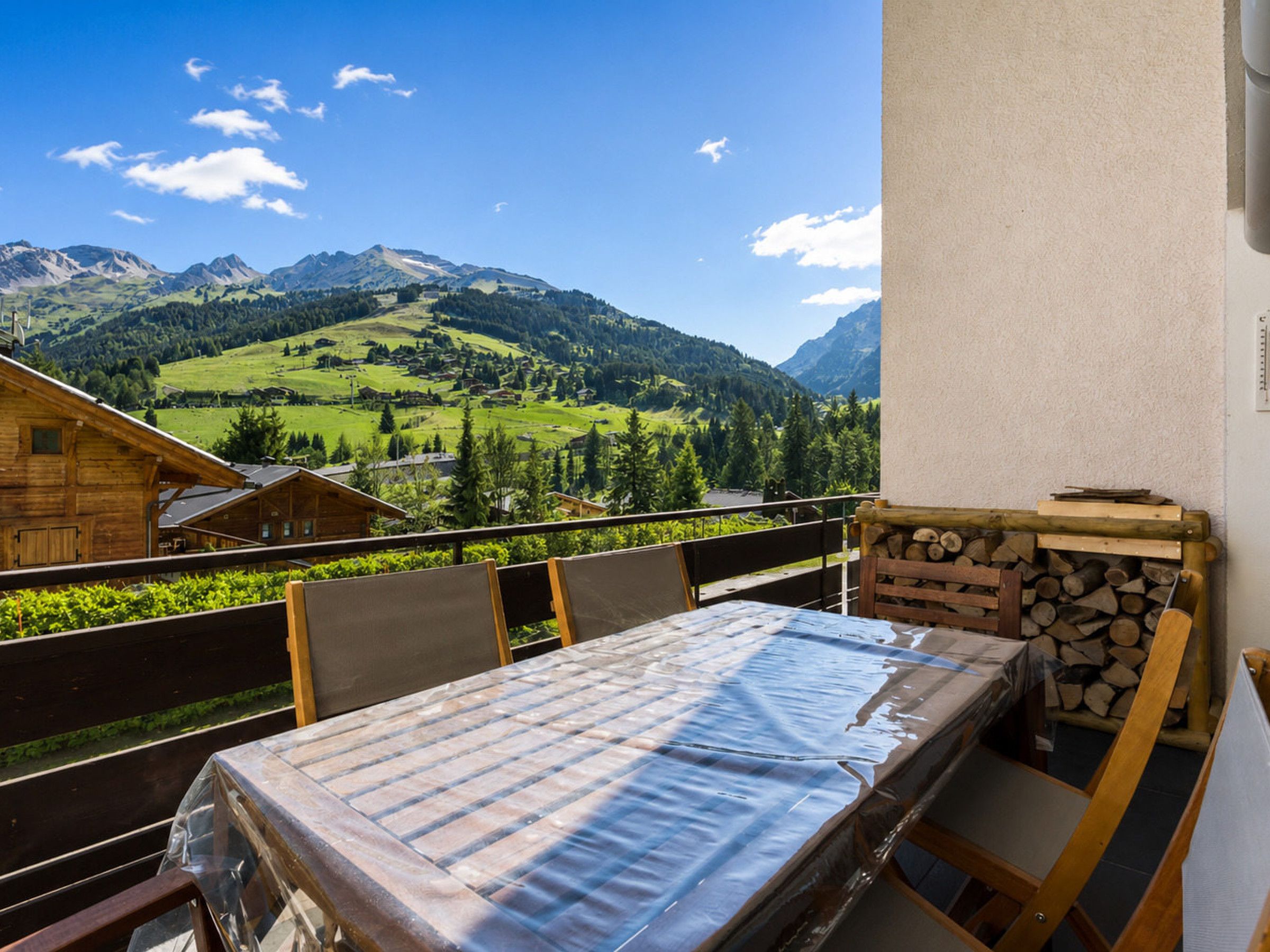 A balcony with a table and chairs, overlooking a mountainous landscape.