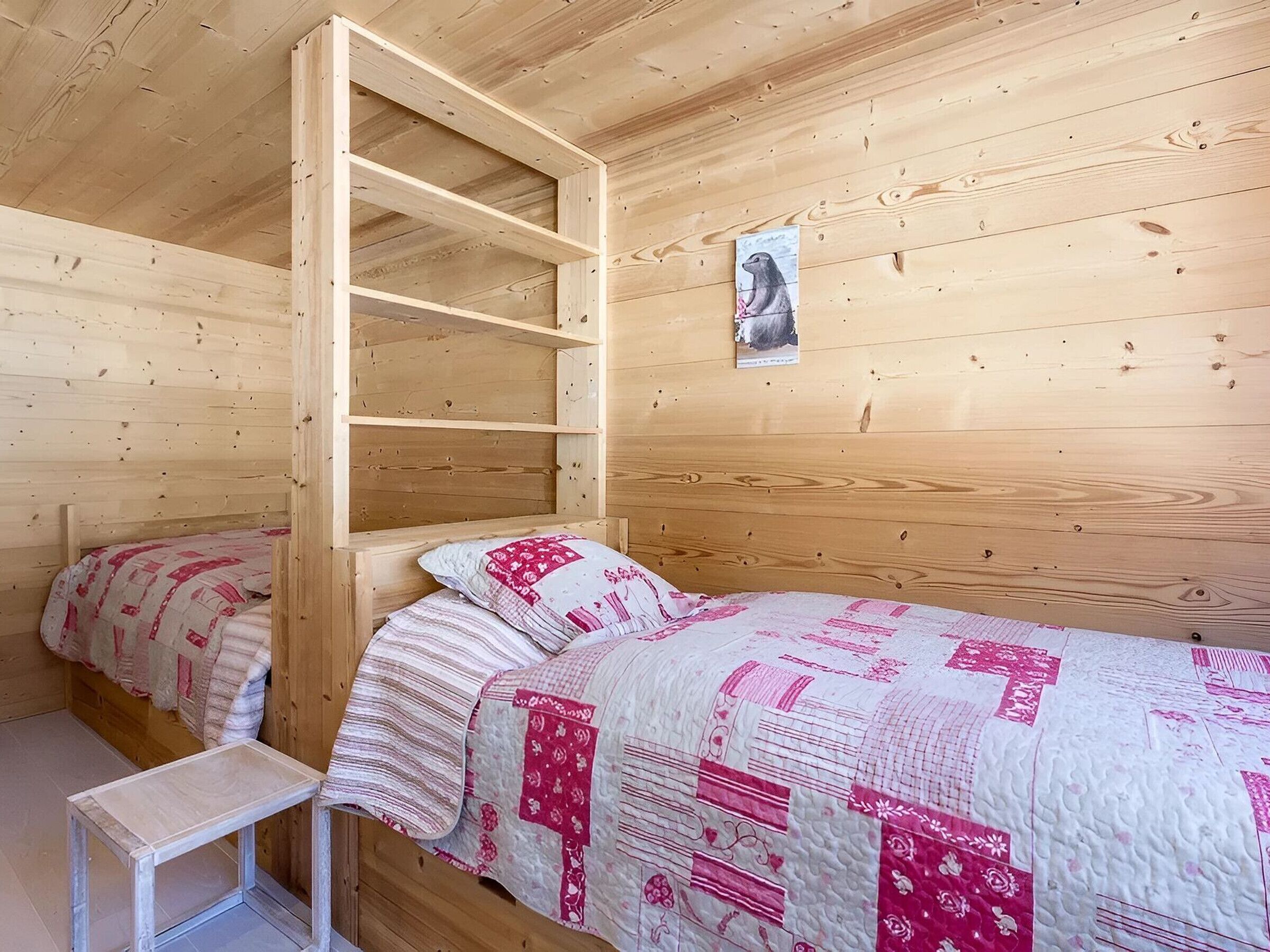 Une chambre dans une cabane en bois, avec un lit superposé, une petite table et une couvre-lit matelassé.