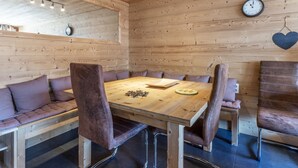 Ein Zimmer mit Holzwänden, einem runden Tisch, Ledersesseln, einer Uhr und einem herzförmigen Schmuckstück.