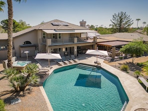 A two-story house with a swimming pool, outdoor seating, and a covered patio area.