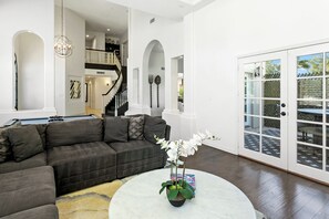 A modern living room with a dark grey sectional sofa, a round coffee table with a plant, and a view of a patio through large glass doors.
