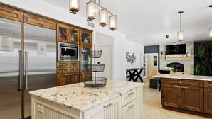 A kitchen with a large island, wooden cabinets, a stainless steel refrigerator, and a built-in oven.