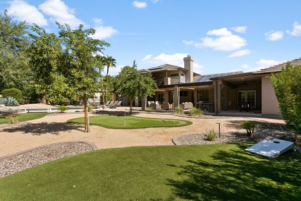 A modern house with a patio, a swimming pool, and a well-maintained lawn.