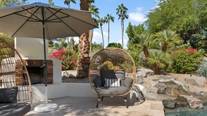 A patio area with a hanging chair, a grill, and a pool. - SWSS Luxury 7BR Estate | Pickleball | Basketball Pool & Hot Tub | Putting Green | Games (Scottsdale)