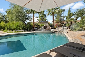 A swimming pool with lounge chairs and a pergola overhead.