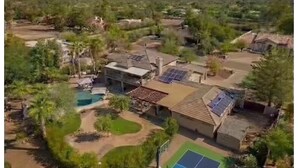 An aerial view of a residential area with a swimming pool, tennis court, and solar panels on rooftops. - SWSS Luxury 7BR Estate | Pickleball | Basketball Pool & Hot Tub | Putting Green | Games (Scottsdale)