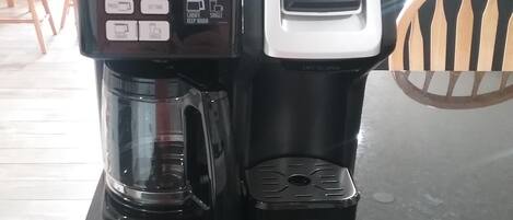 Una cafetera con pantalla digital, jarra y depósito para las gotas sobre una encimera.