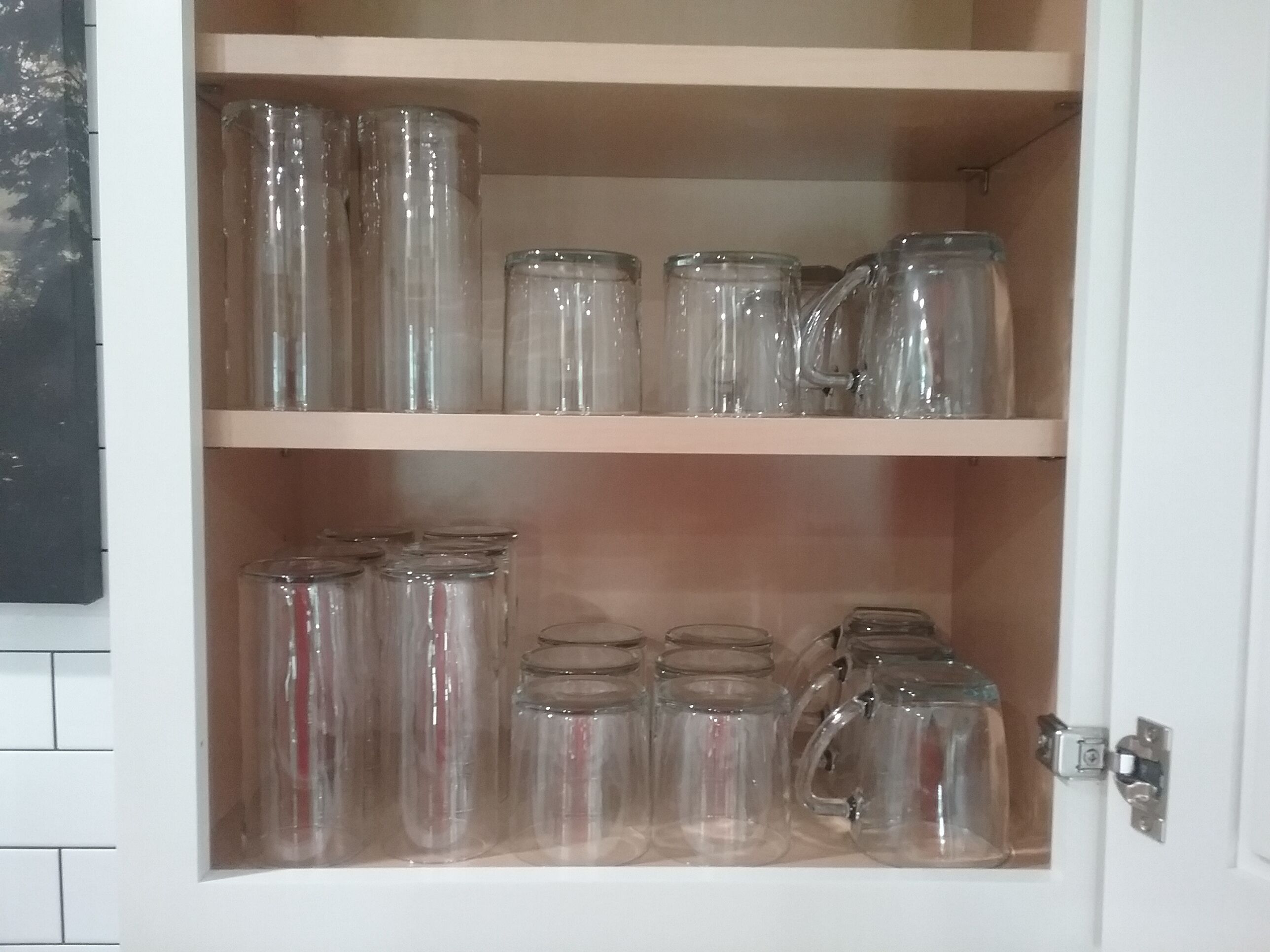 Ett skåp med två hyllor som innehåller olika typer av glasbehållare.