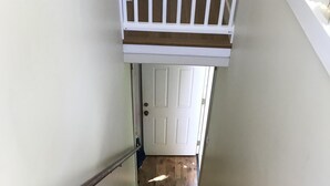 Unes escales de fusta amb barana blanca que porten a una porta blanca.