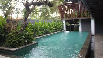 Une piscine entourée d’une terrasse en bois et d’une végétation luxuriante.