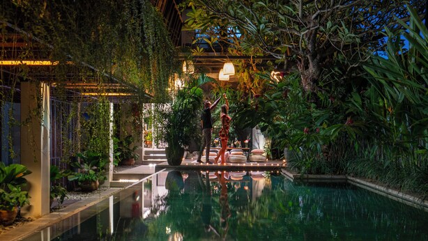 An indoor pool with a reflection of the surroundings, surrounded by lush greenery and plants. - The Kemilau Hotel & Villa Canggu (Tibubeneng)