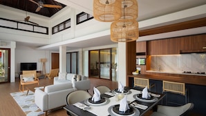 A spacious living area with a dining table set for four, a sofa, and a television in the background. - The Kemilau Hotel & Villa Canggu (Tibubeneng)