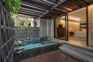 A spa area with a hot tub, wooden deck, and a view into a modern bedroom with a bed and a nightstand. - The Kemilau Hotel & Villa Canggu (Tibubeneng)