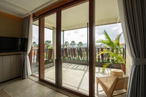 Ein Balkon mit Schiebetür, einem Korbstuhl und einem Blumentopf.