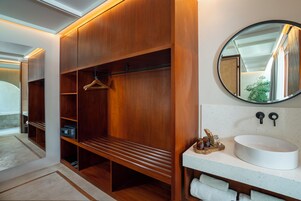 A modern bathroom with a wooden vanity, a round mirror, and a built-in bench.