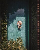 Una persona en una piscina con una mesa redonda y alimentos.