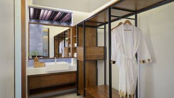 A modern bathroom with a wooden vanity, a large mirror, and a robe hanging on a rack.