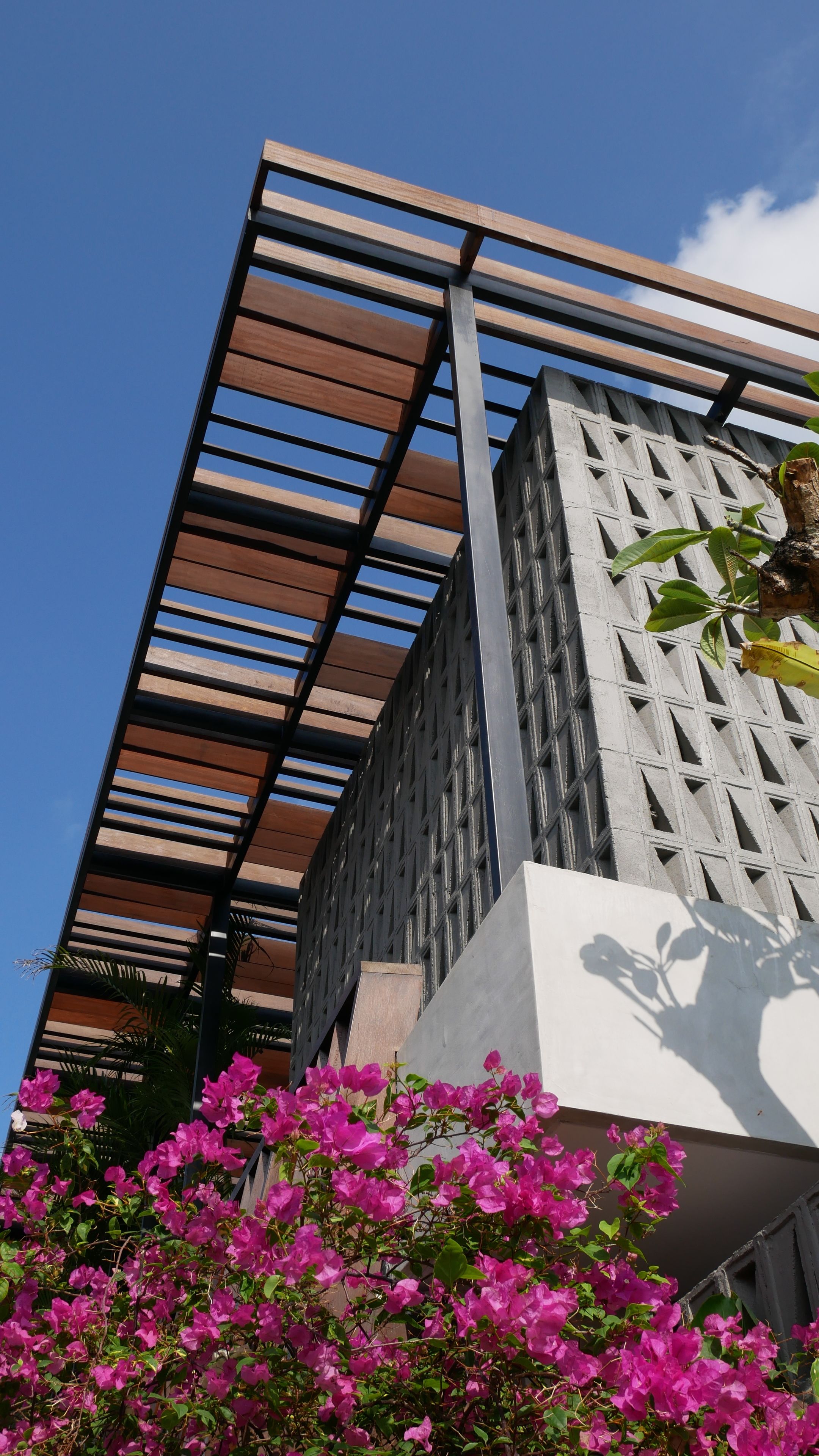 Un edificio moderno con techo de listones de madera y fachada de hormigón.