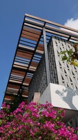 Un edificio moderno con techo de listones de madera y fachada de hormigón.