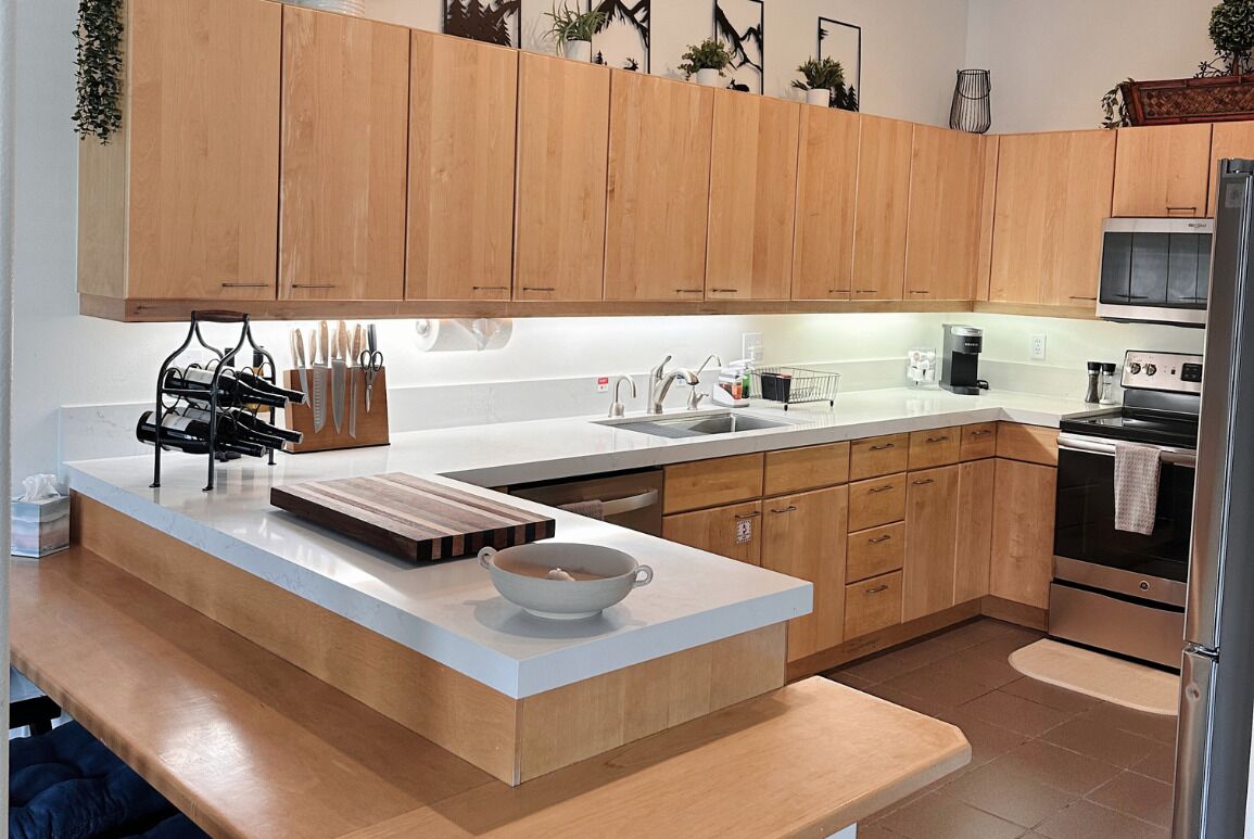 A modern kitchen with wooden cabinets, a white countertop, and stainless steel appliances.